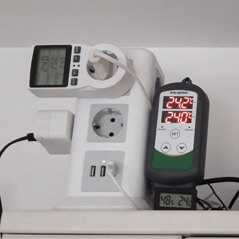 Steckdose mit USB-Anschlüssen und Temperaturmessgerät, Anzeige von 24 und 27 Grad.